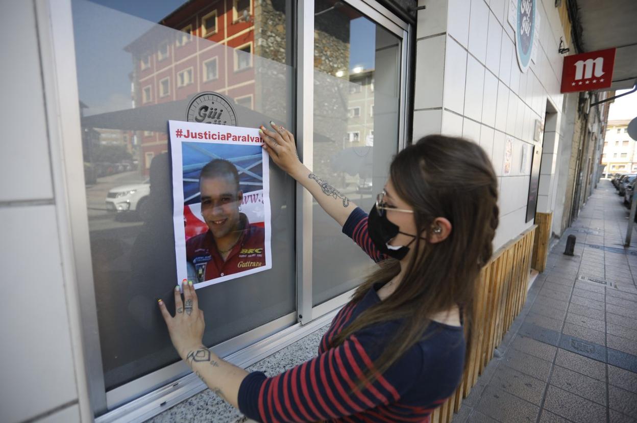 Una joven pega un cartel en el que se pide justicia para Iván Castro. 