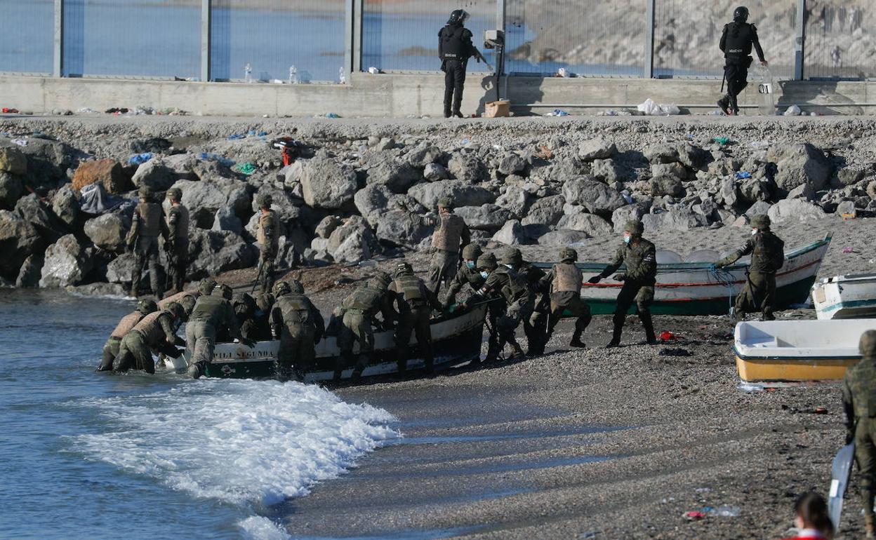 Militares españoles, con migrantes procedentes de Marruecos en la playa del Tarajal, en Ceuta 