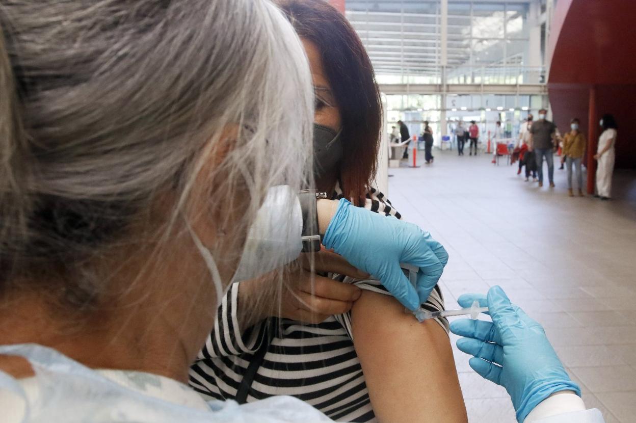 Una mujer recibe una dosis en el palacio de La Guía mientras otras personas aguardan su turno. 