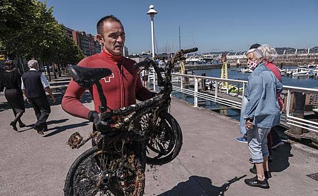 Uno de los buzos con una bicicleta encontrada en el fondo del puerto.
