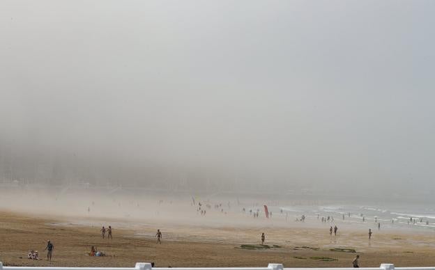 La gijonesa playa de San Lorenzo, irreconocible bajo la niebla que obligó a prohibir el baño a partir de primera hora de la tarde. 