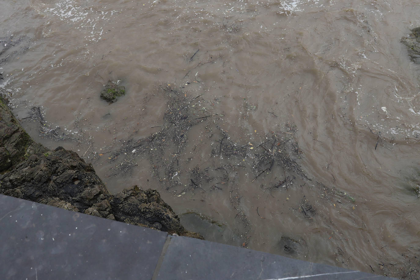 Gijón cierra al baño el tramo entre las escaleras 12 y 15 de la playa de San Lorenzo por los alivios al río Piles provocados por el temporal de lluvias. 