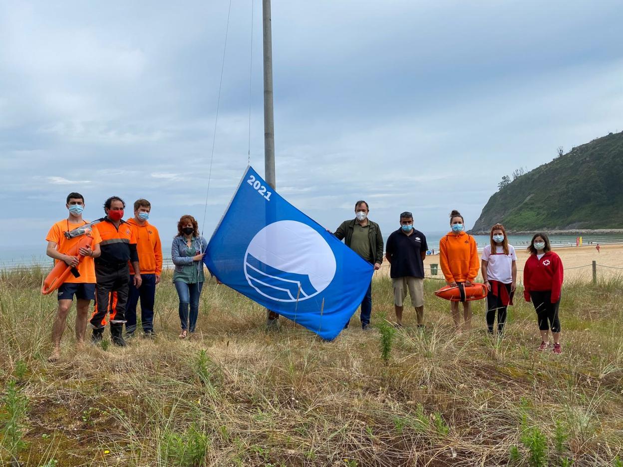 El alcalde, Alejandro Vega, y la edil Lorena Villar izan la bandera azul en Rodiles junto a miembros del equipo de salvamento, Protección Civil y Cruz Roja. 