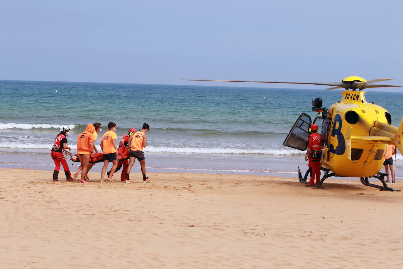 El helicóptero del Servicio de Emergencias del Principado realizó esta mañana un simulacro en la playa de Rodiles. La actuación, que contaba con la participación de más de veinte profesionales, despertó la curiosidad entre los bañistas. El objetivo de este simulacro es enseñar a los socorristas cómo actuar en caso de emergencia durante este verano. El equipo rescatador explicó cuál es la mejor zona para el aterrizaje y cómo deben prepararse.