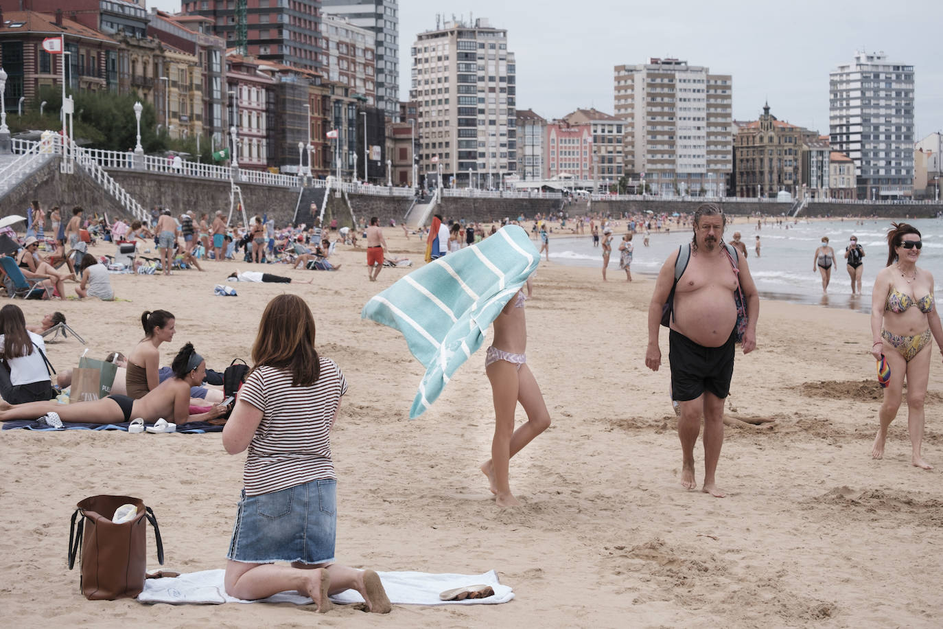 Está siendo un verano atípico en la costa asturiana, pero el mal tiempo no ha impedido que los bañistas se lancen a la playa de San Lorenzo con ganas de disfrutar del día. Algunos pasean, otros leen con la ropa puesta y los más valientes se atreven a darse un chapuzón. Cualquier plan es preferible a quedarse en casa.