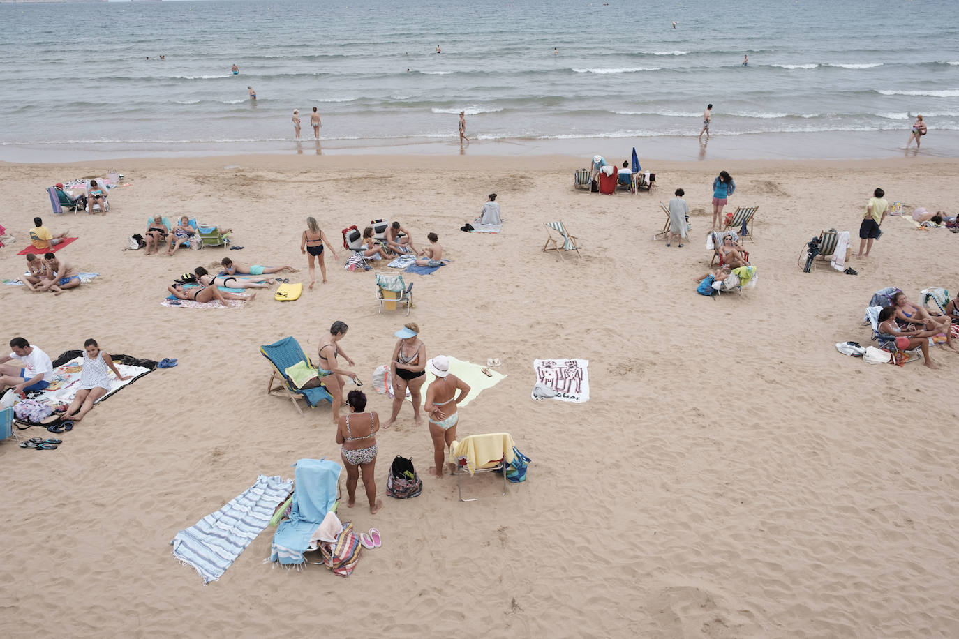 Está siendo un verano atípico en la costa asturiana, pero el mal tiempo no ha impedido que los bañistas se lancen a la playa de San Lorenzo con ganas de disfrutar del día. Algunos pasean, otros leen con la ropa puesta y los más valientes se atreven a darse un chapuzón. Cualquier plan es preferible a quedarse en casa.