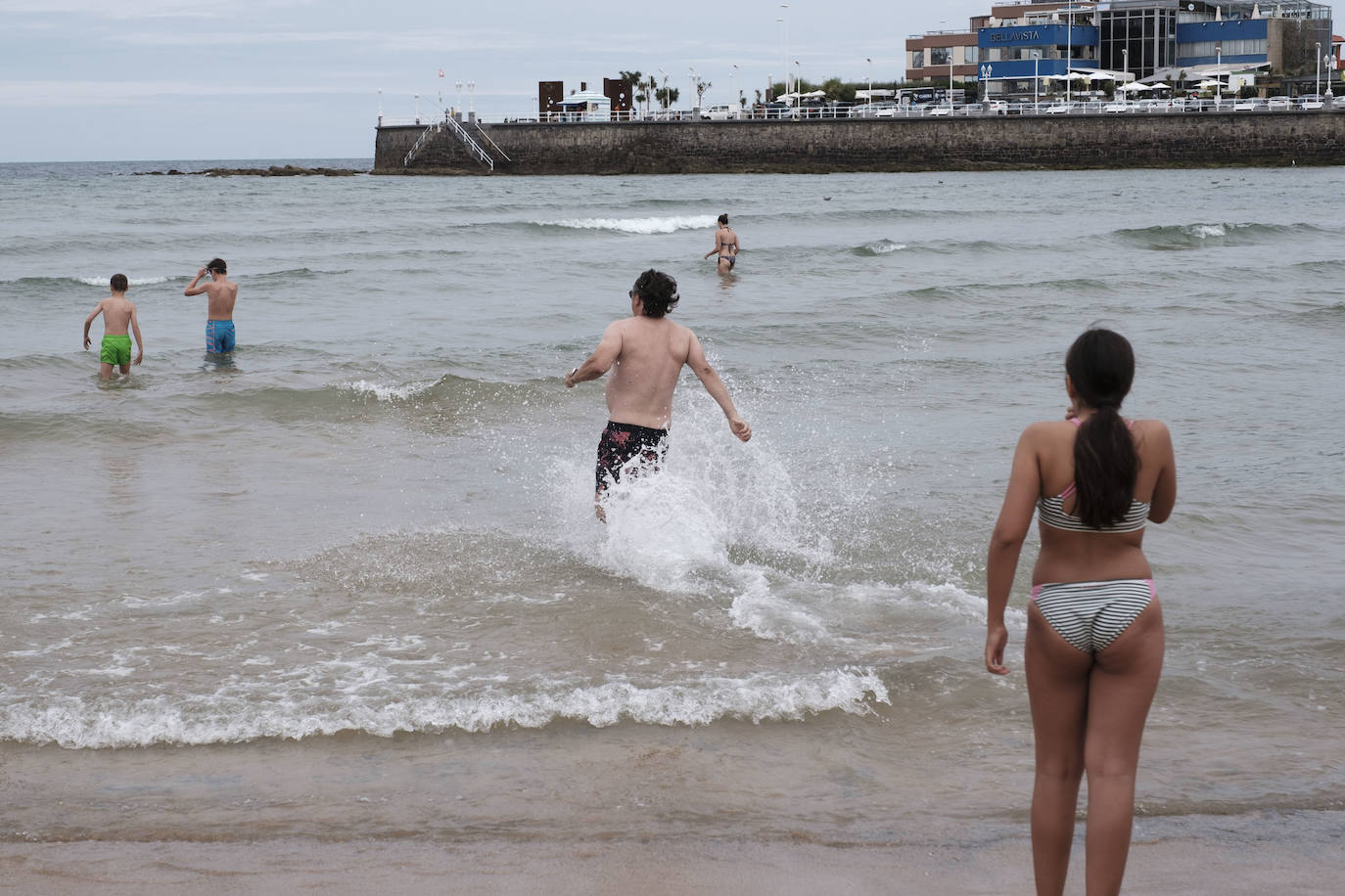 Está siendo un verano atípico en la costa asturiana, pero el mal tiempo no ha impedido que los bañistas se lancen a la playa de San Lorenzo con ganas de disfrutar del día. Algunos pasean, otros leen con la ropa puesta y los más valientes se atreven a darse un chapuzón. Cualquier plan es preferible a quedarse en casa.