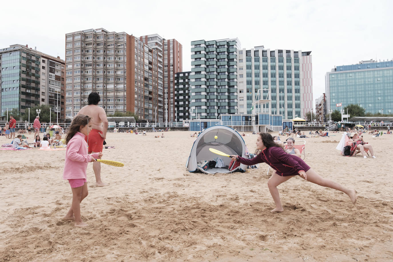 Está siendo un verano atípico en la costa asturiana, pero el mal tiempo no ha impedido que los bañistas se lancen a la playa de San Lorenzo con ganas de disfrutar del día. Algunos pasean, otros leen con la ropa puesta y los más valientes se atreven a darse un chapuzón. Cualquier plan es preferible a quedarse en casa.