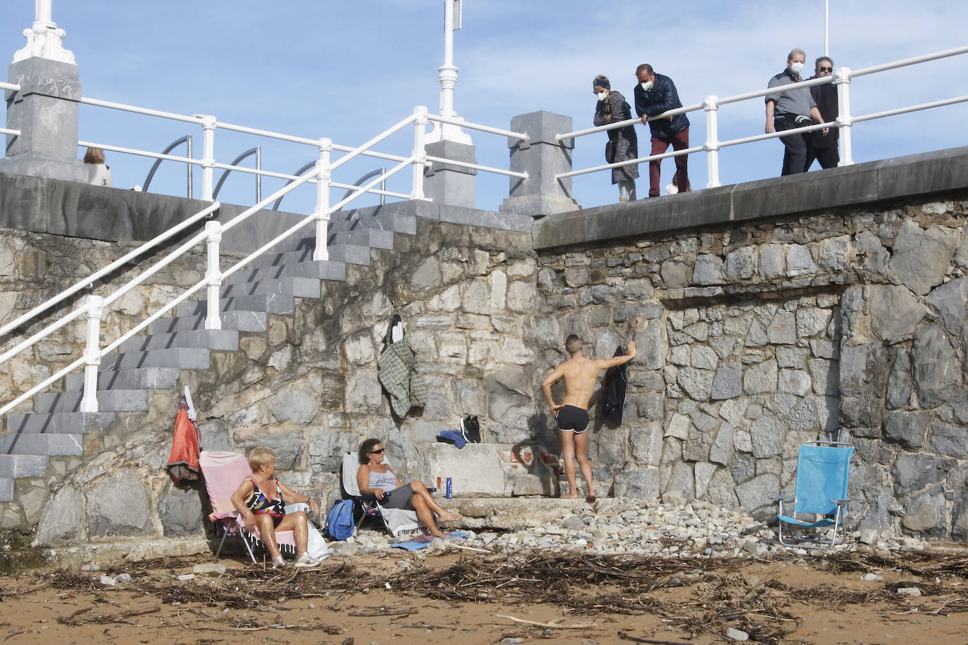 Nery, Pili y Álvaro, usuarios habituales del tostaderu, se quejan de que Emulsa no recoge la madera de las riadas y tienen que ser ellos quienes acondicionen el espacio para poder tomar el sol.