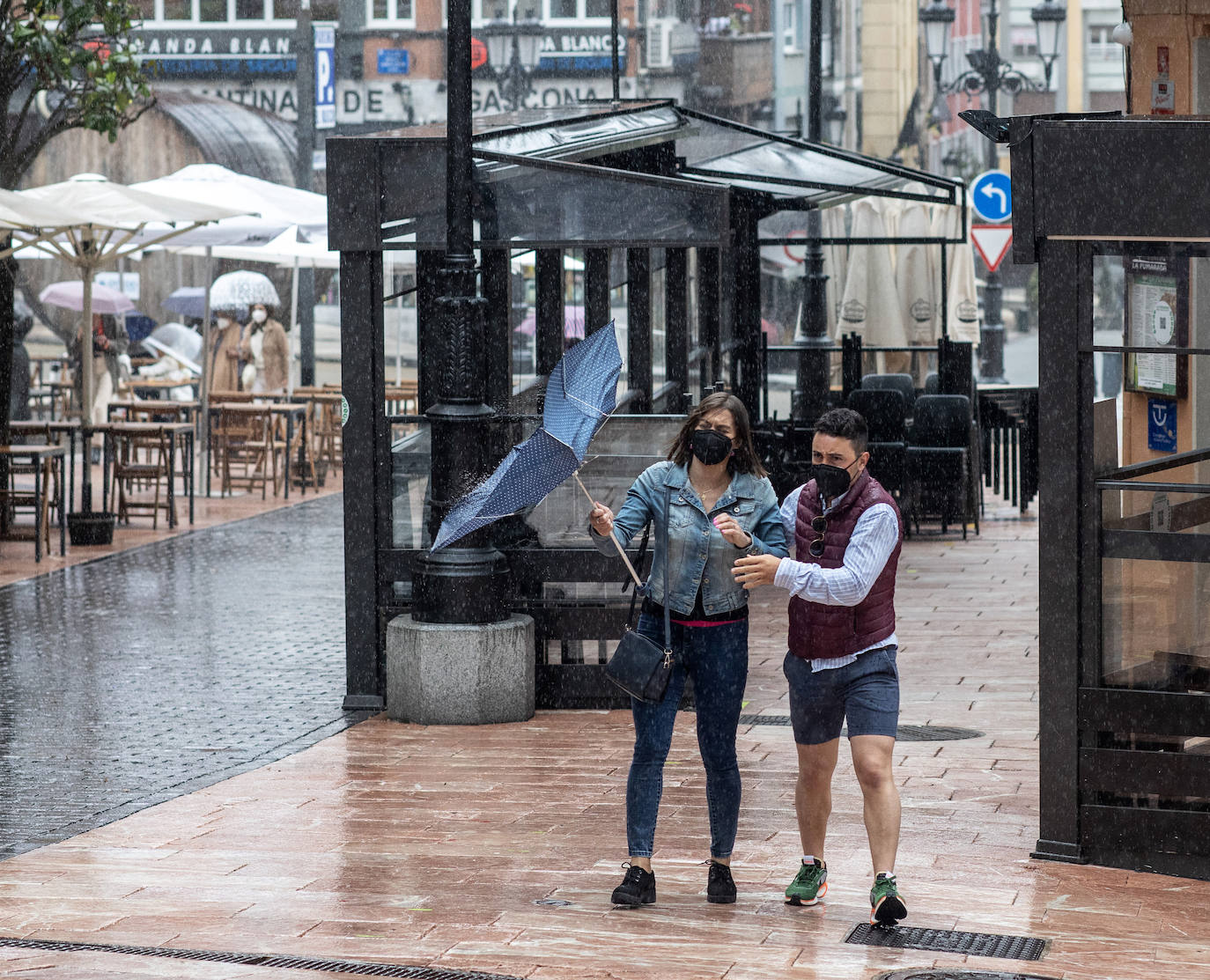 Una pareja se pelea contra el paraguas en pleno temporal en Oviedo.