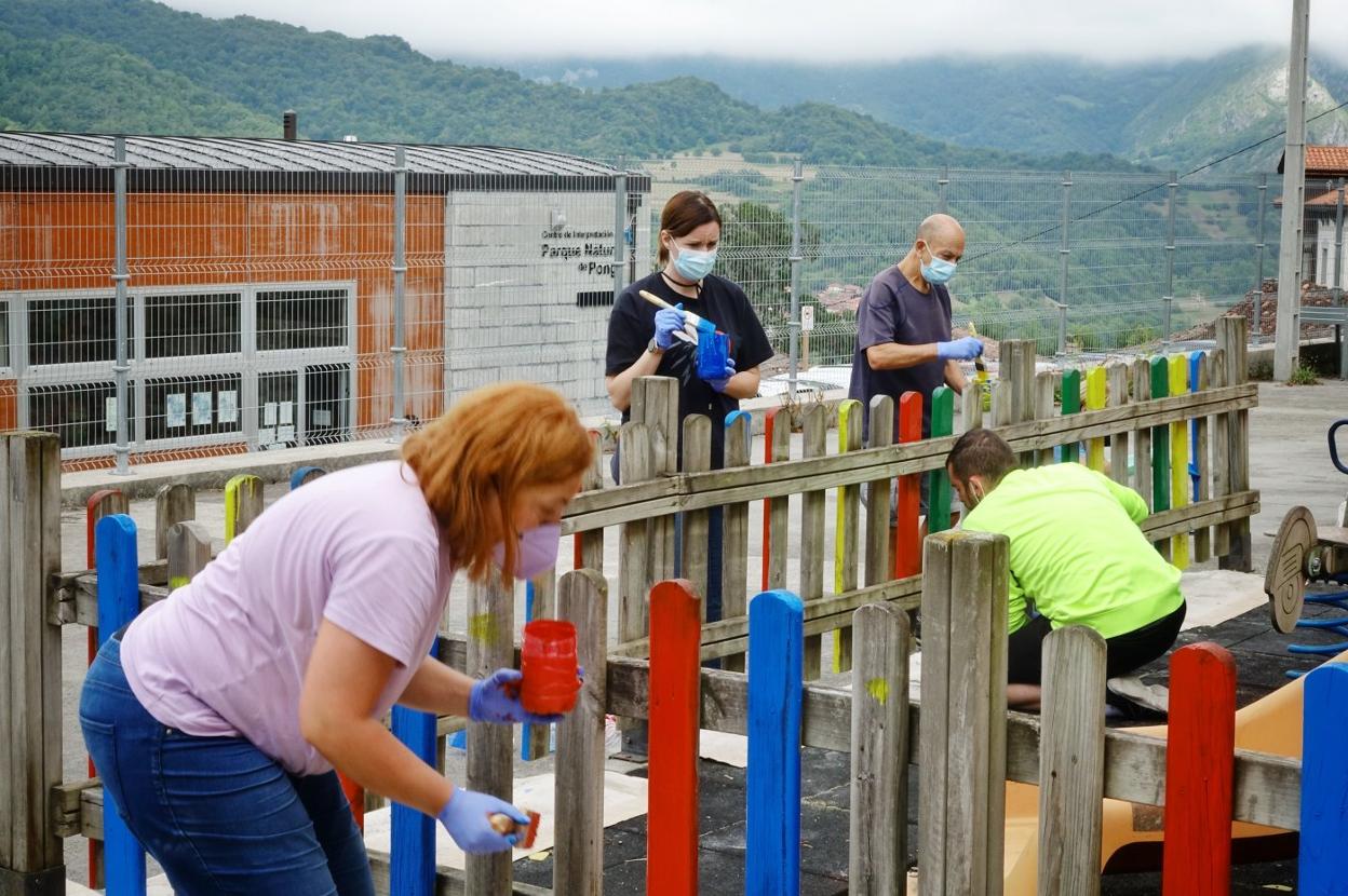 Voluntarios pintando el parque del patio escolar. 