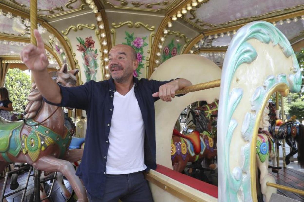 El peluquero Javier Cofiño ultima sus vacaciones en la tierrina, en el carrusel del paseo de Begoña de Gijón. 