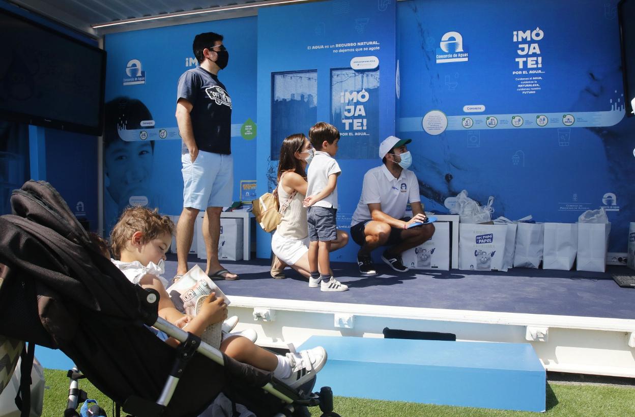 La pequeña ojea el libro de Cadasa, junto al puesto. 