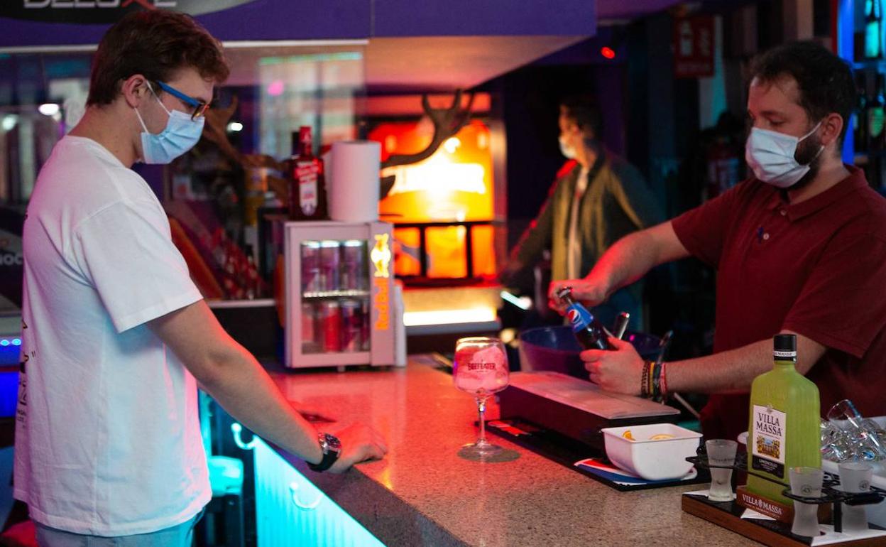 Un camarero sirve una bebida a un cliente en un bar.