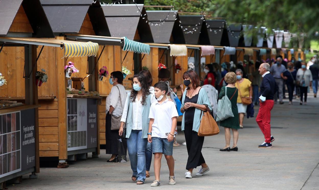 Varias personas, ayer al mediodía, paseando ante el mercadillo de artesanía que se celebra durante las fiestas en el Campo. 