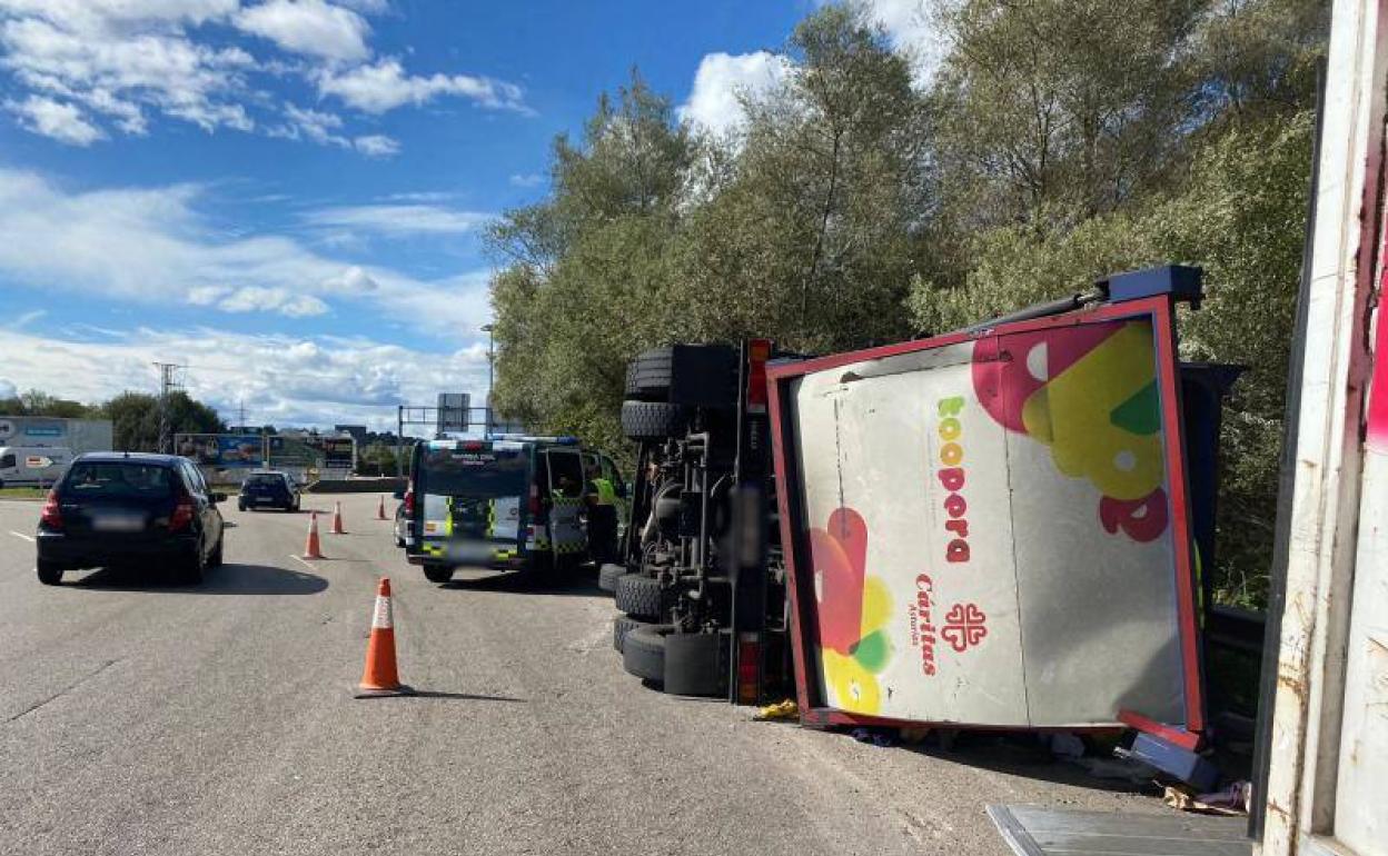 Vuelca un camión lleno de ropa en una rotonda a la entrada de Lugones