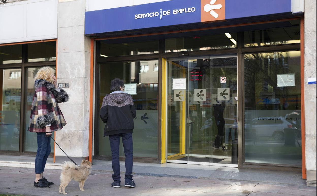 Dos personas a la entrada de una oficina del Servicio de Empleo.