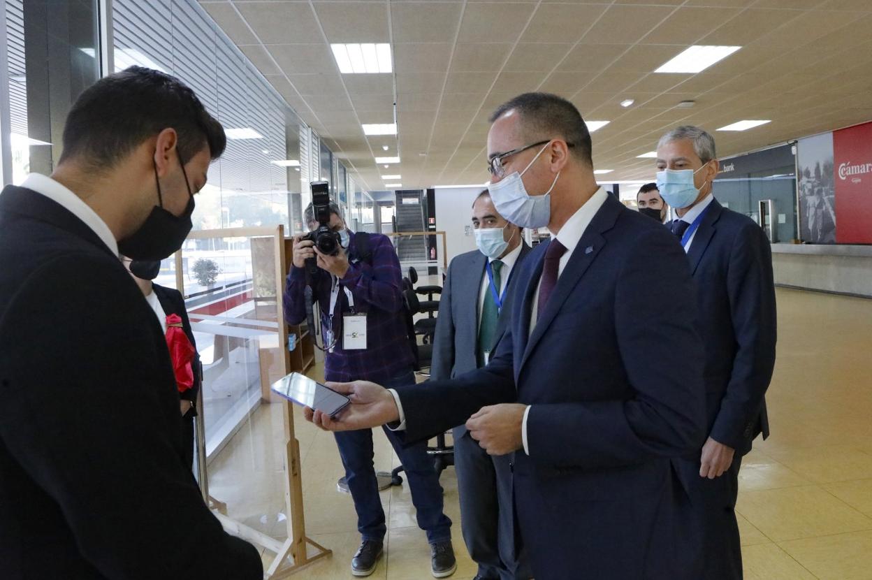 Pablo Fernández muestra su certificado de vacunación. A la derecha, uno de los estands comerciales. 
