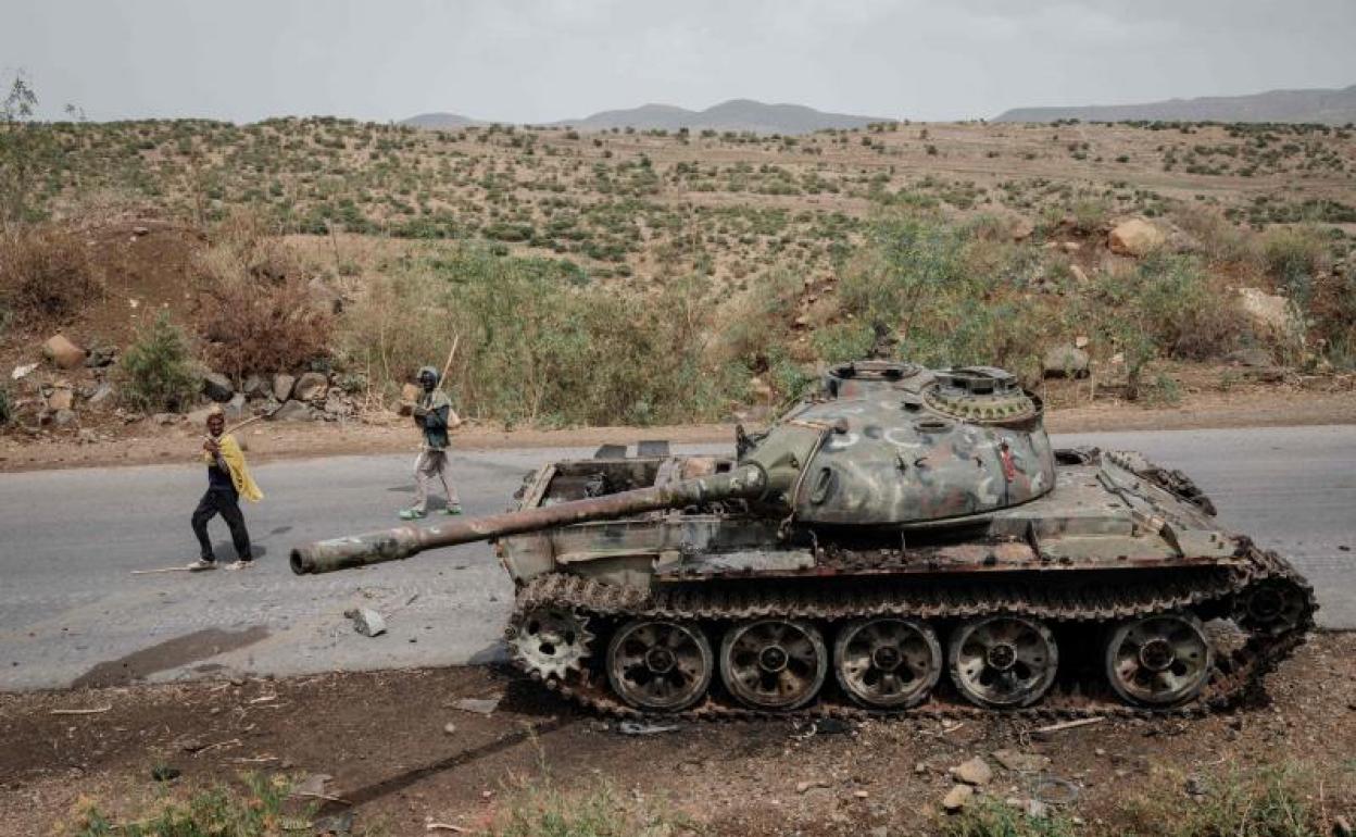 Dos granjeros pasan junto a los restos de un tanque calcinado en la región de Tigray.