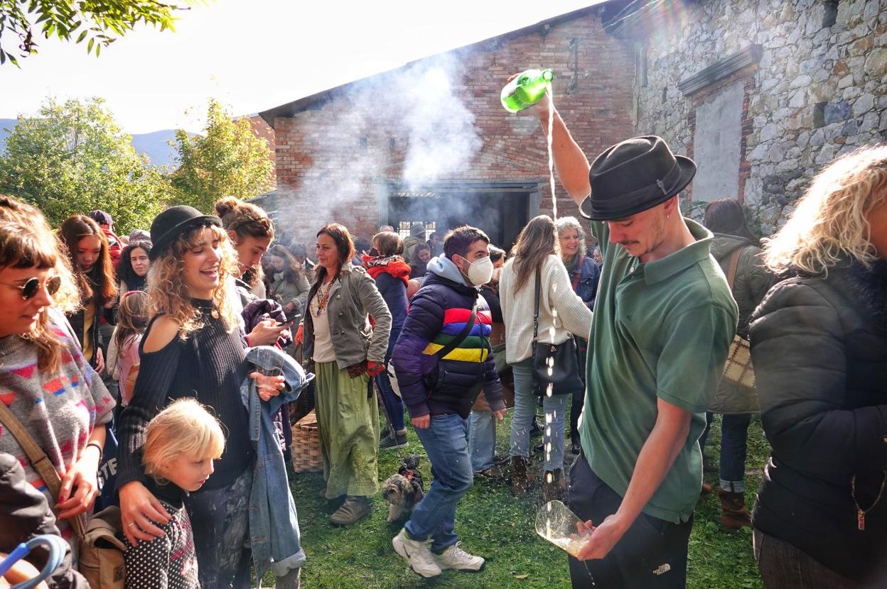 Rodrigo Cuevas, con la hucha para recaudar fondos para el tejado.El joven Nicolás Felgueroso escancia sidra en el patio de La Benéfica, en Infiesto. 