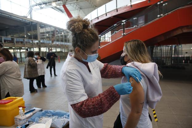 Una enfermera administra la dosis de refuerzo a una de las personas citadas ayer en el Palacio de Deportes de La Guía, en Gijón. 