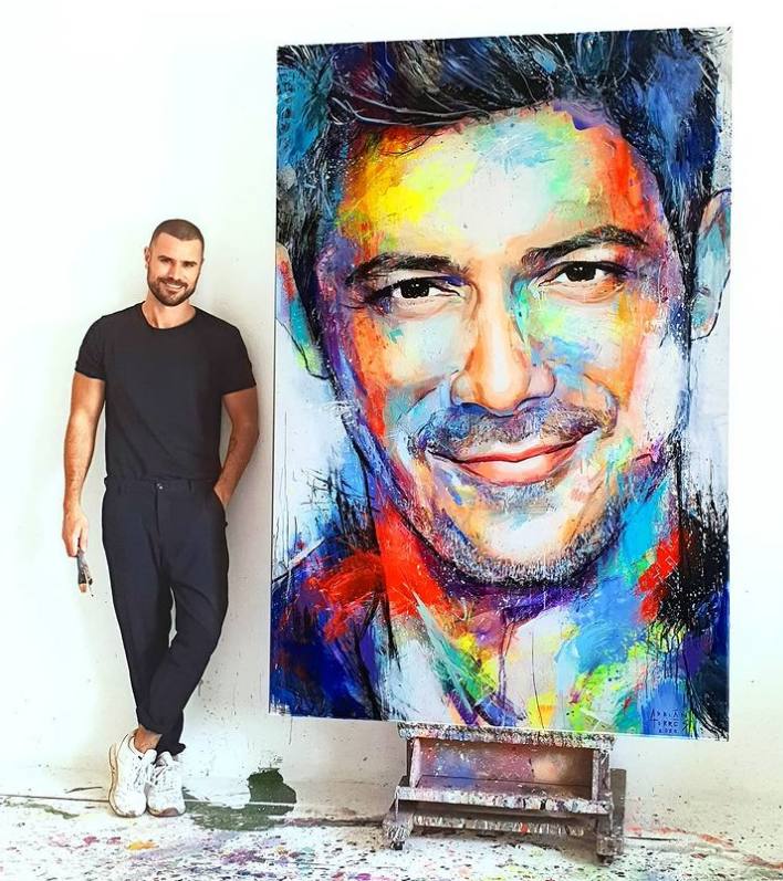 El artista Adrián Torres posa con el retrato de Alejandro Sanz.