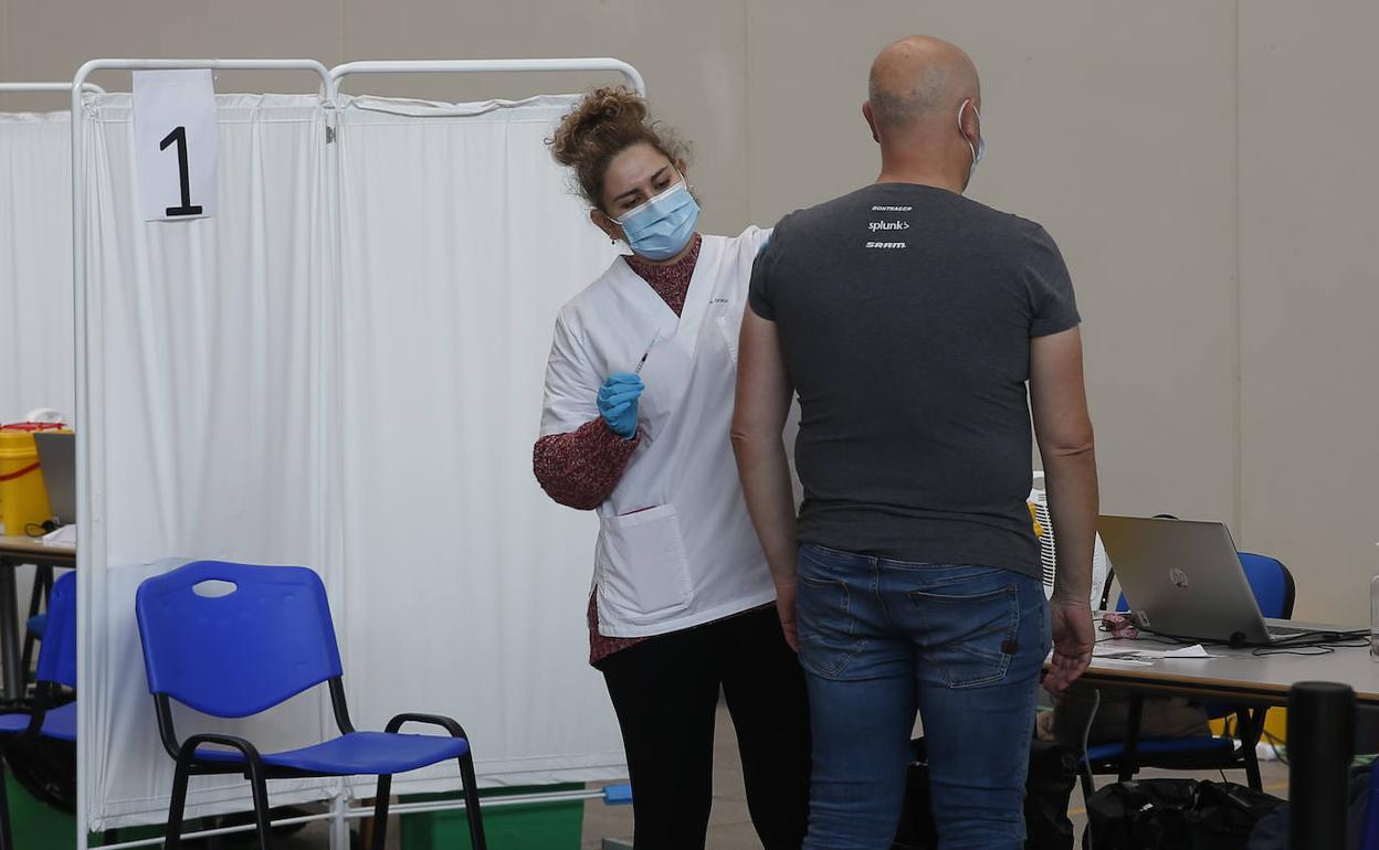 Una sanitaria vacuna a un hombre en el Palacio de Deportes de Gijón. 