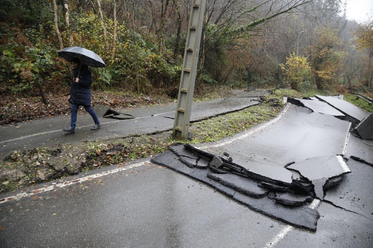 Langreo. Una hombre camina por la zona de la carretera LA-7, de acceso de Ciaño a La Nueva, donde se hundió la calzada. 