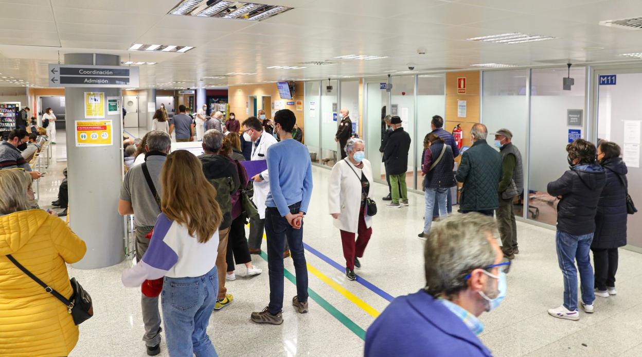 Usuarios del Hospital de Cabueñes aguardan su turno en la zona de información a la entrada del centro hospitalario gijonés. 