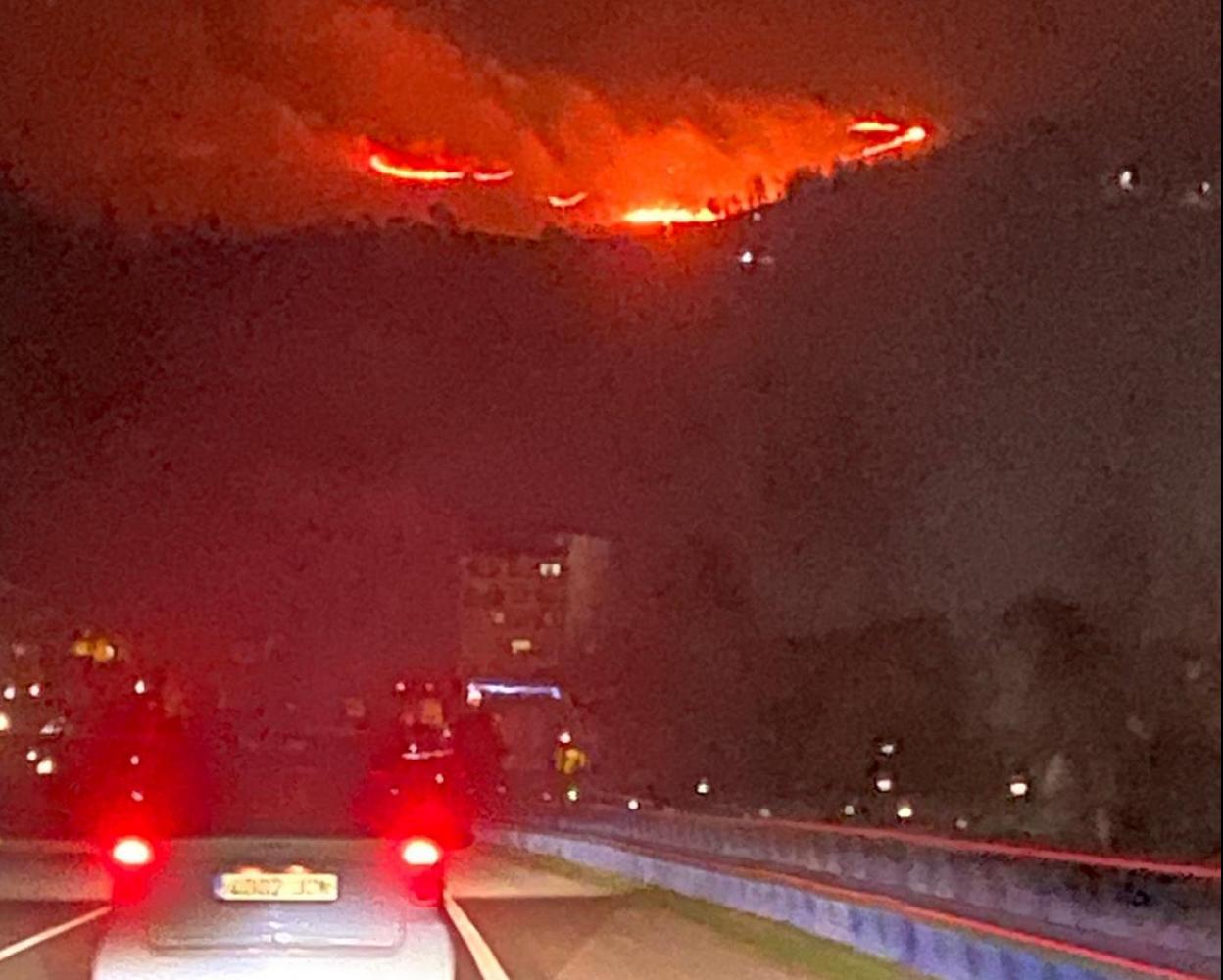 Uno de los incendios forestales que permanecían activos anoche, visto desde la carretera AS-17 en San Martín del Rey Aurelio. 