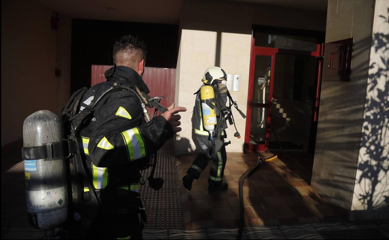 Dos bomberos acceden al edificio donde se produjo el incendio. 