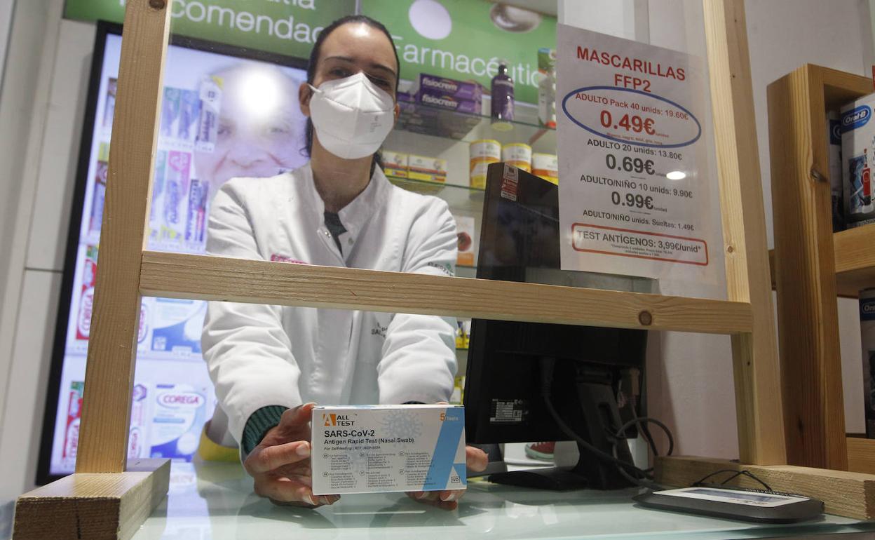 Una framacéutica muestra una caja de test de antígenos en una farmacia de Gijón. 