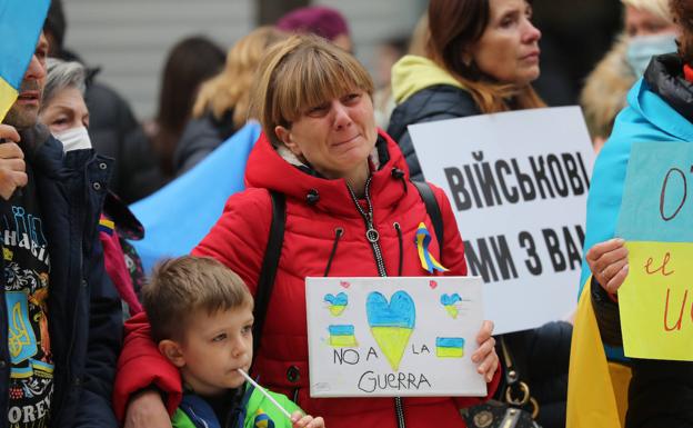 Una mujer y un niño que asistieron a la concentración en Gijón sostiene un cartel, entre lágrimas, contra la guerra que asedia a Ucrania 