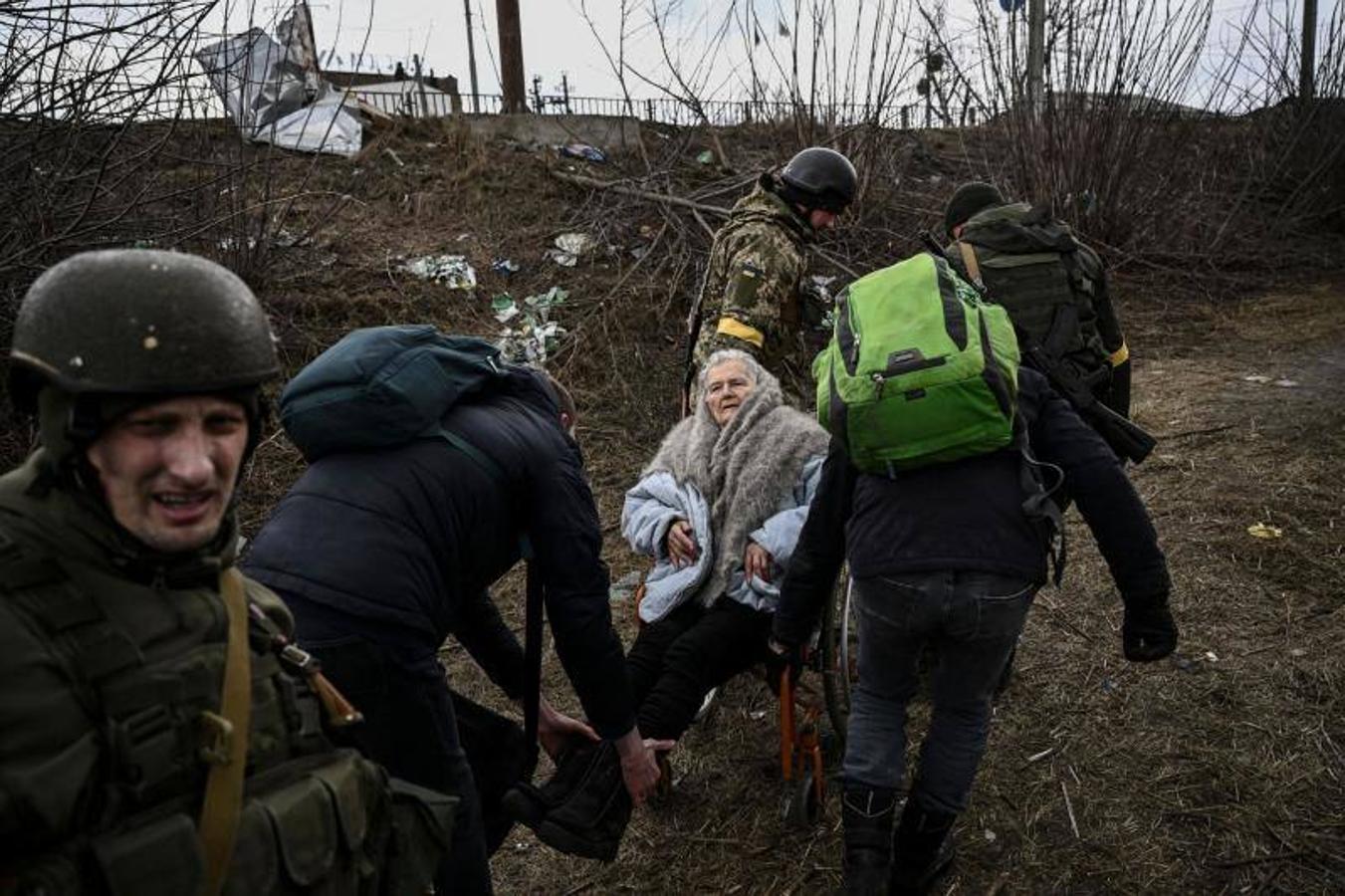 Voluntarios ayudan a una anciana a salir de Irpin a través del corredor humanitario.