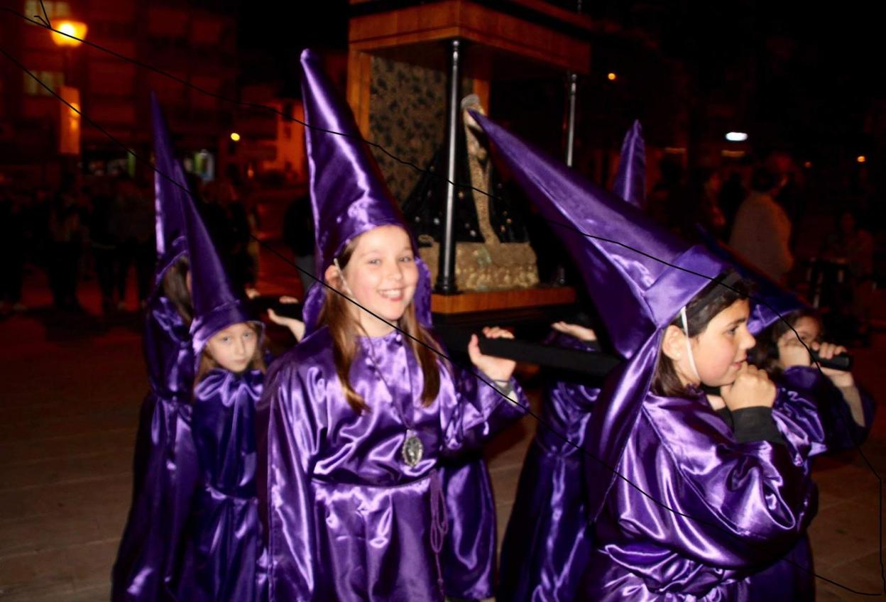 Un grupo de niños porta el paso de 'La Dolorina' en la procesión de Viernes Santo. 