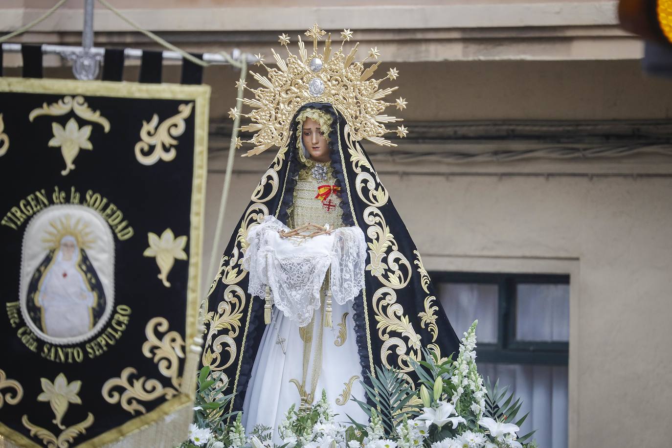 La Ilustre Hermandad de la Santa Vera Cruz abrió camino desde el Campo Valdés para dirigirse a Sebastián Miranda, seguidos por la Hermandad de la Misecordia, portadora de la imagen de San Juan Evangelista y, tras ellos, los integrantes de la Ilustre Cofradía del Santo Sepulcro portaban sobre sus hombros a la virgen de la Soledad, rodeada de flores blancas y ataviada con un manto azul noche y bordados dorados.