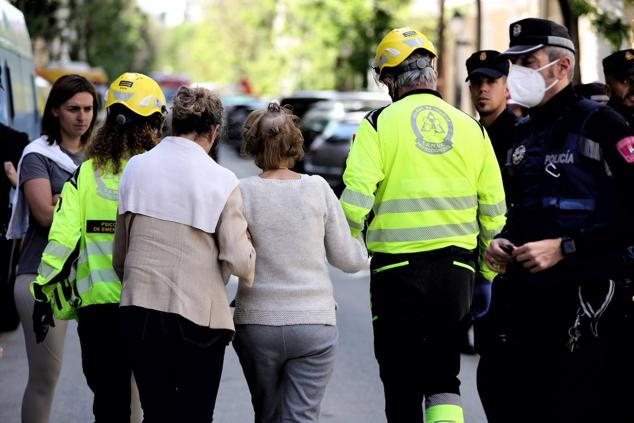 Los bomberos acompañan a una zona segura a varios personas que se encontraban en las inmediaciones del edificio.