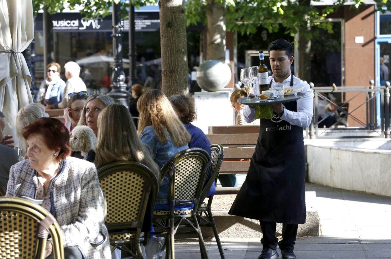 Un camarero sirve unas consumiciones en una terraza de Gijón. 