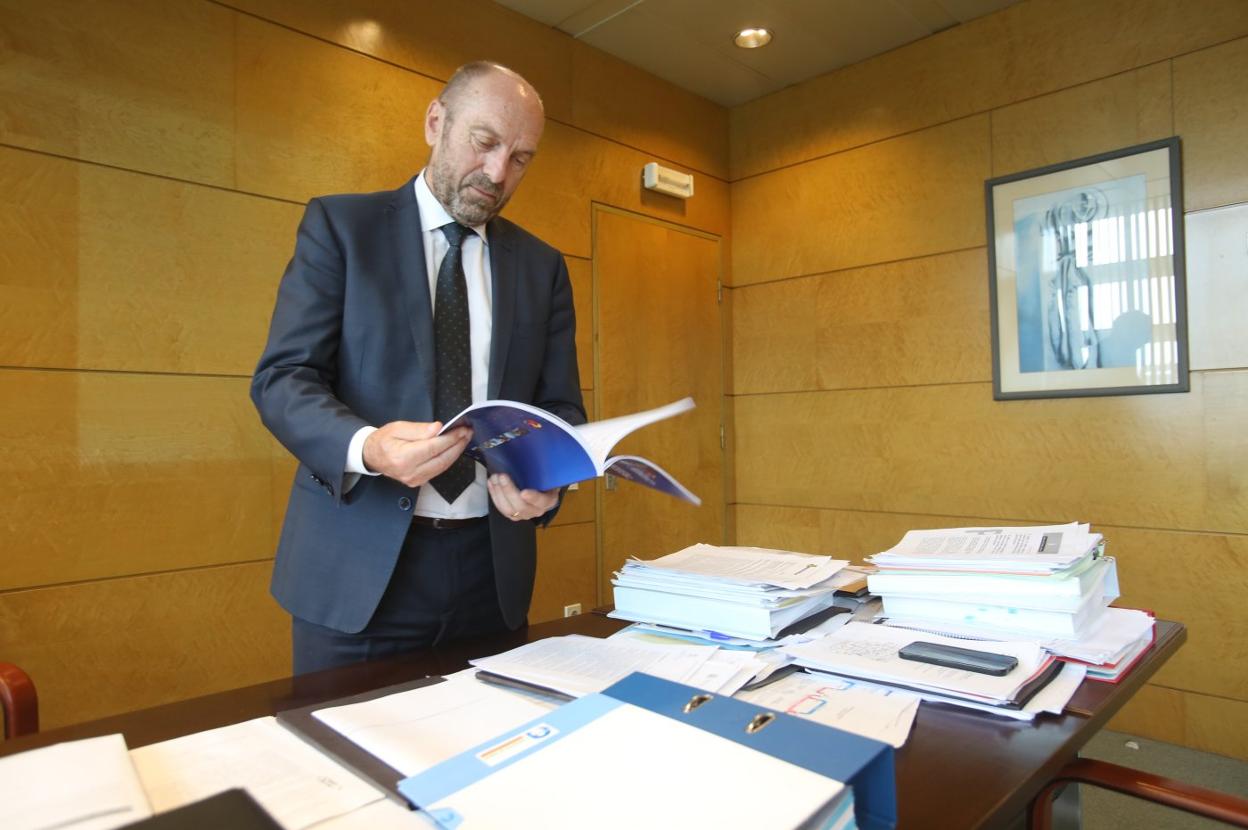 Juan Cofiño repasa unos informes en la mesa de su despacho, llena de documentos y carpetas. 