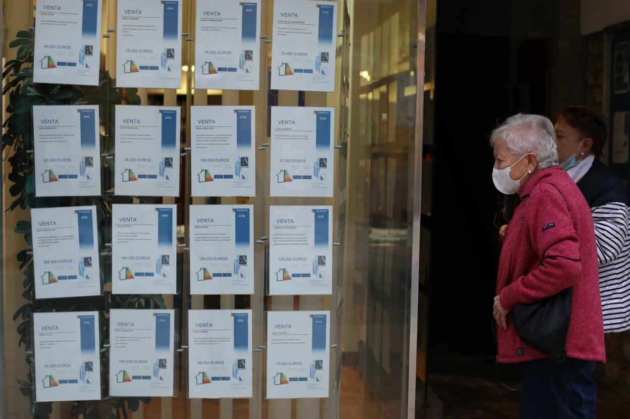 Dos mujeres pasan por delante del escaparate de una agencia inmobiliaria. 