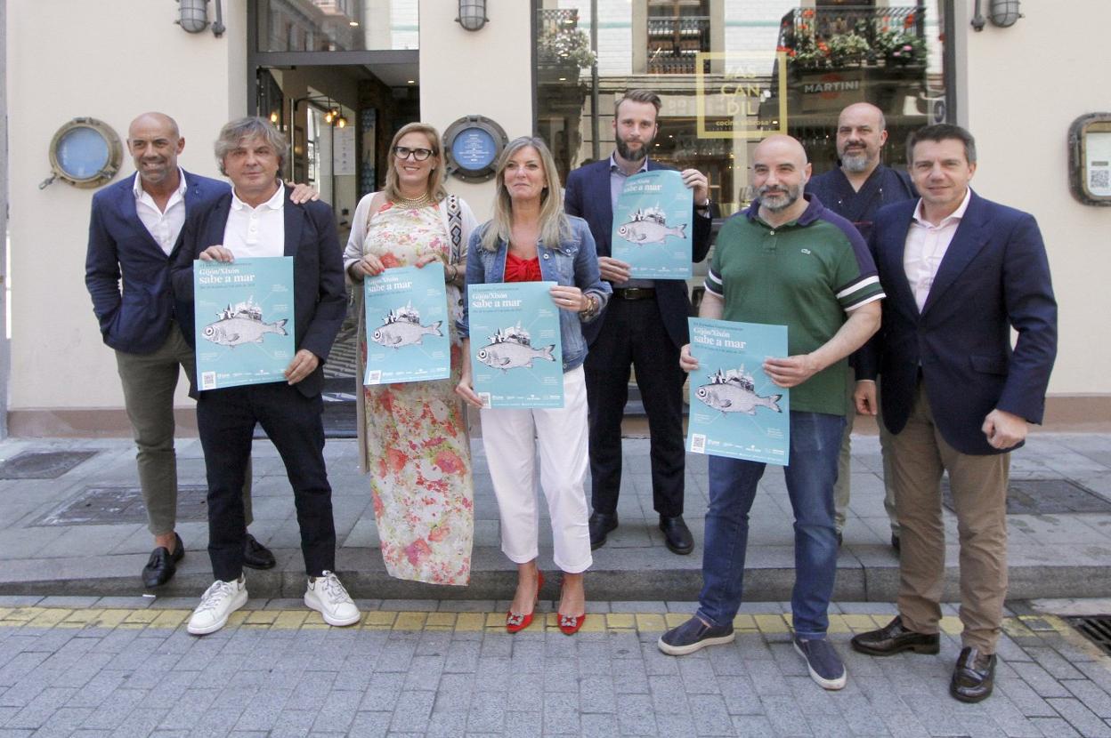 Álex López, Ángel Lorenzo, Lara Martínez, Graciela Blanco, Daniel Martínez Junquera, Santos Tejón, José Luis Camacho y José Luis Álvarez Almeida, con los carteles de las jornadas 'Gijón sabe a mar' frente al restaurante Zascandil. 