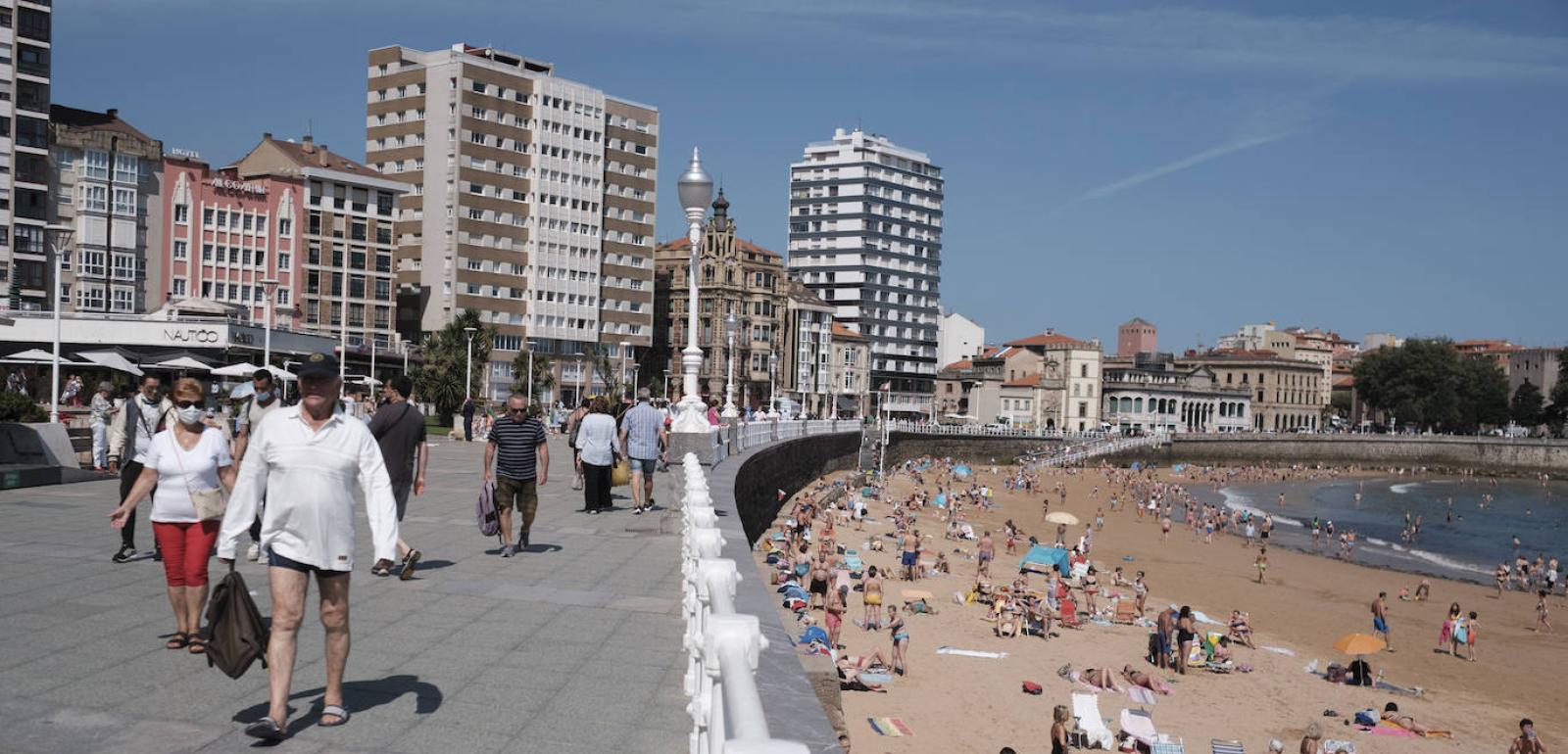 La playa de San Lorenzo, en Gijón, con paseantes y bañistas.