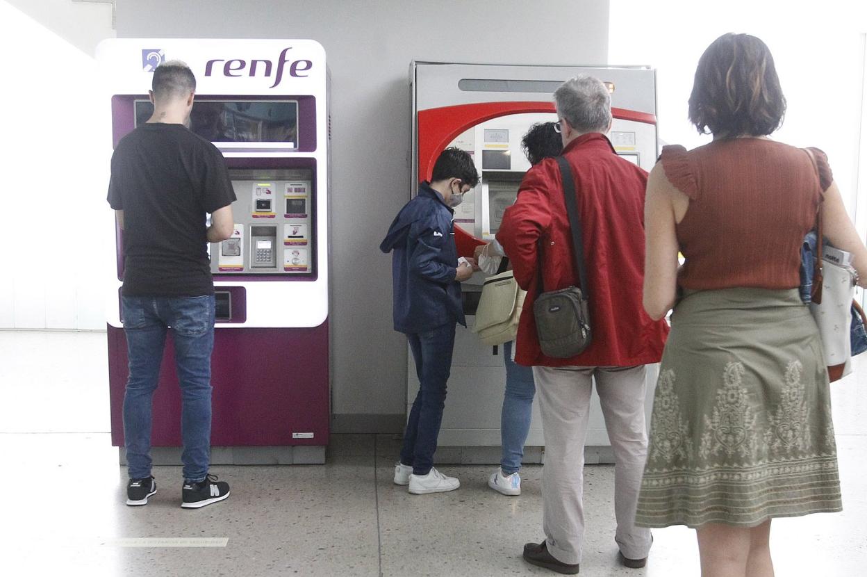 Usuarios hacen cola ante una de las máquinas expendedoras de los abonos, en la estación de Gijón. 