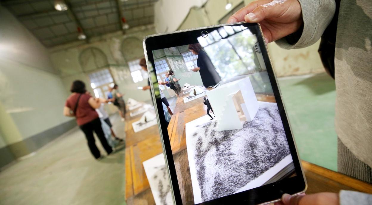 Uno de los participantes muestra a cámara una tablet durante la actividad de realidad aumentada. 