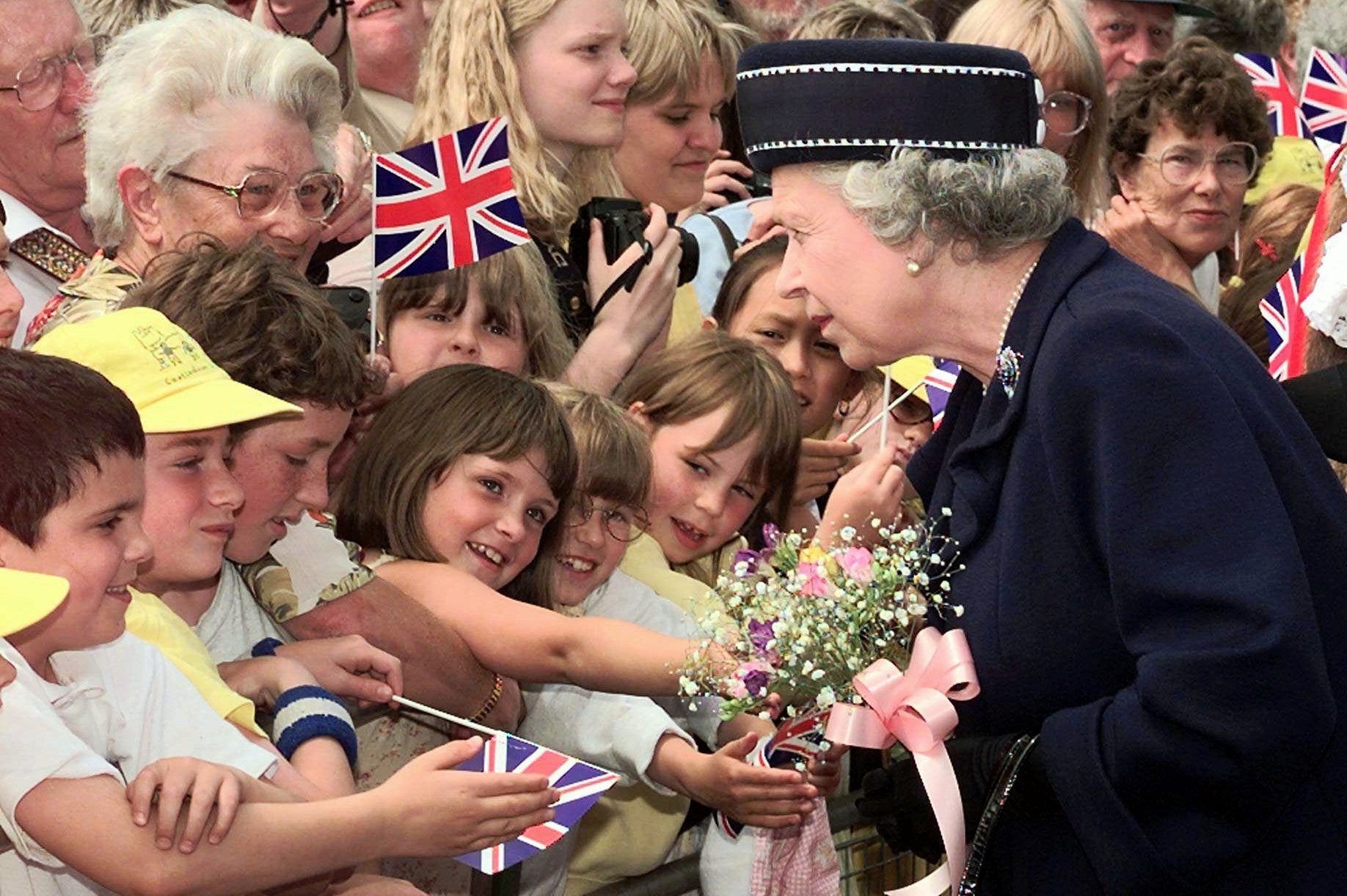 La reina recibe un ramo de flores de manos de una niña en el puerto de Hastings, al sur de Inglaterra, el 6 de junio de 1997.