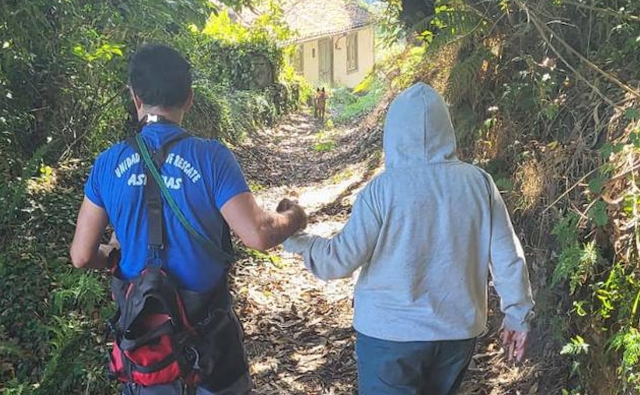 Al fondo, 'Chuli', el perro que localizó a la mujer desaparecida (derecha), que está acompañada por un voluntario de la Unidad Canina de Rescate del Principado. 