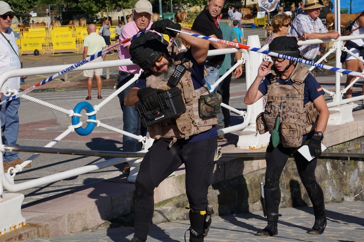Los especialistas de la Armada salen de la playa con la caja en la que depositaron el objeto. 