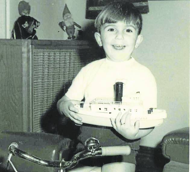 De niño, con su bicicleta y su barco.