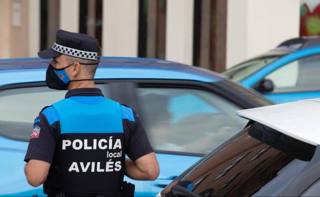 Un agente de la Policía Local junto a un coche patrulla.