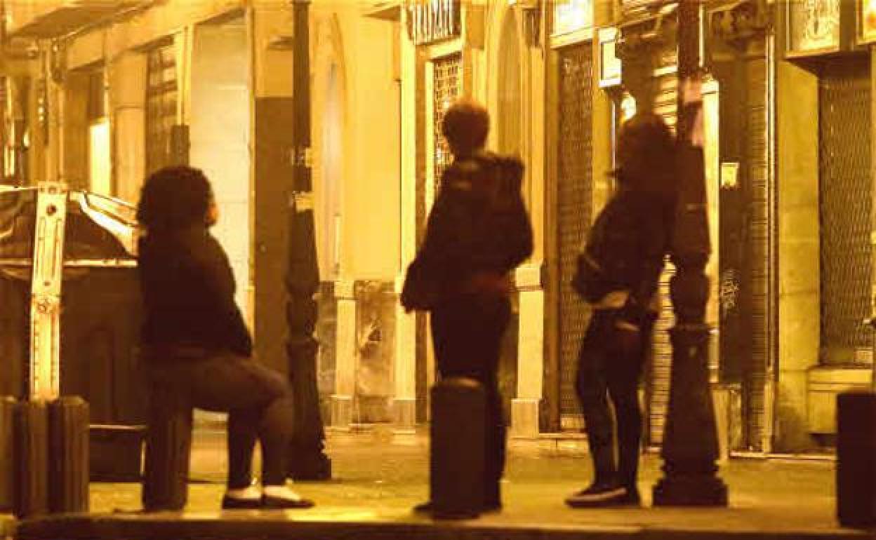 Varias mujeres que ejercen la prostitución esperan en una calle.